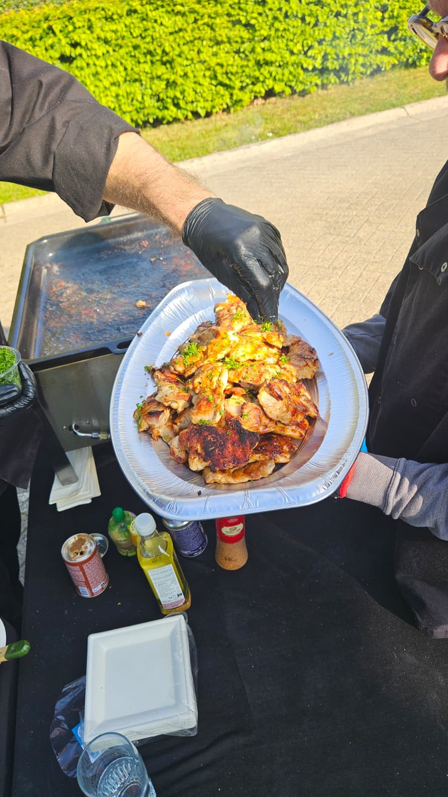 Adriano in koksjas, lachend naast de grill